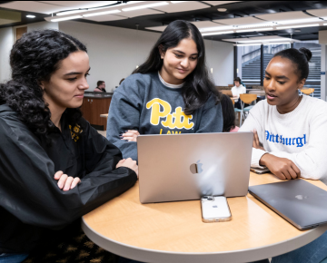 Students looking at laptop in lounge